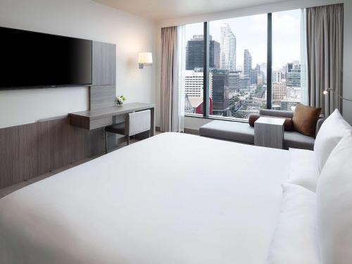 曼谷Novotel Bangkok Platinum Pratunam的一间酒店客房,设有一张大床和一个大窗户
