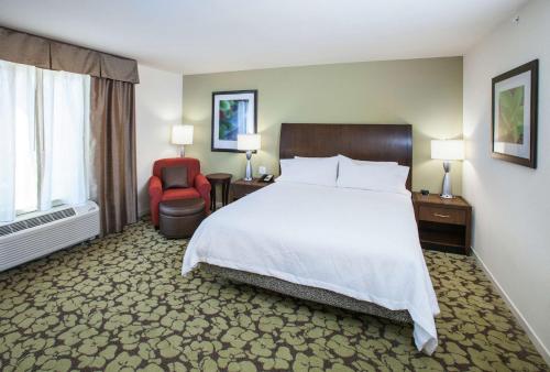 弗洛伍德杰克逊/弗洛伍德希尔顿花园酒店的配有一张床和一把椅子的酒店客房