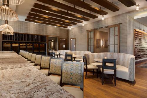 格林维尔格林维尔市中心瑞尔普雷斯希尔顿合博套房酒店的一间带桌椅和葡萄酒瓶的餐厅