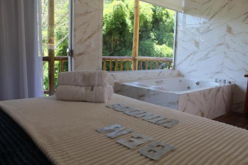 贡萨尔维斯Chales Maria Flor的一间卧室配有一张带浴缸和水槽的床。