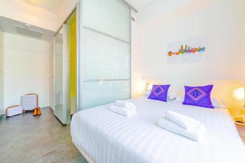里昂Residence Montempo Lyon Cite Internationale的卧室配有一张带紫色枕头的大型白色床。
