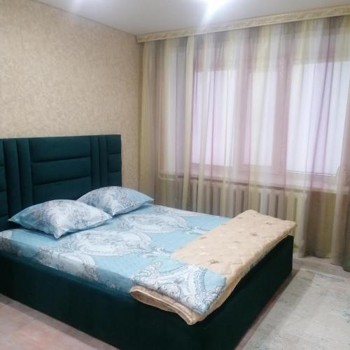RudnyКвартира трёхкомнатная г. Рудный的卧室内的一张带蓝色棉被和枕头的床