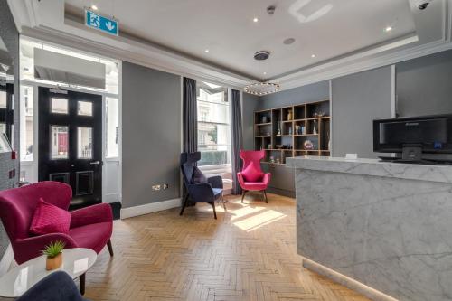 伦敦伦敦维多利亚莫宁顿酒店的一间带粉红色椅子的客厅和一间酒吧