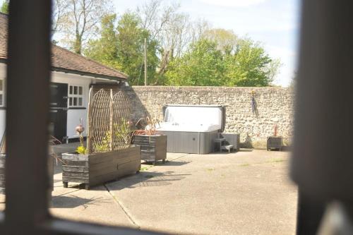 EarthamChillout!! Sussex Flint Cottage- HotTub - Goodwood的后院设有石墙和浴缸