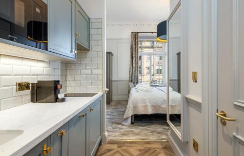爱丁堡RÌGH Residences - George Street的一间厨房,配有蓝色橱柜和一张位于客房内的床