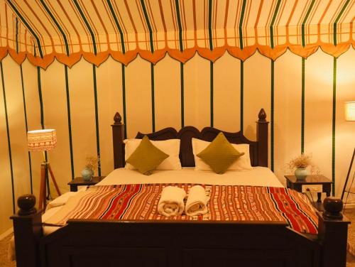 山姆Venture Desert Camp Jaisalmer的一间卧室配有一张带两个凉鞋的床。