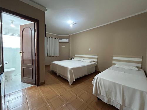 大普拉亚Ibericas Praia Hotel的一间带两张床的卧室和一间带浴缸的浴室