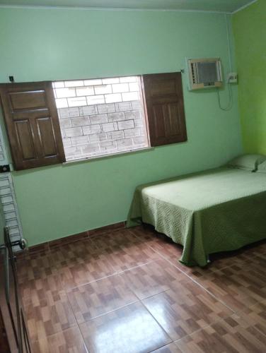 帕林廷斯Casa Parintins的一间卧室设有一张床和一个窗户,铺有木地板