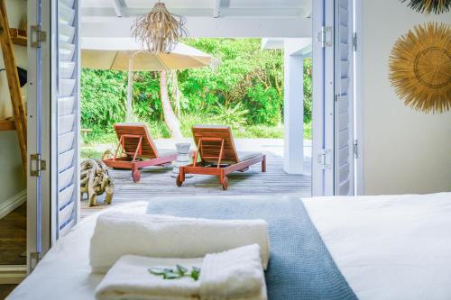 韦斯特布鲁克Luxury Private Beach Villa centrally located.的一间卧室配有一张床、两把椅子和一把遮阳伞