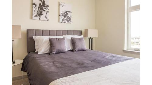路易斯威尔Stunning Nulu 1BR CozySuites Unit 03的一间卧室配有一张大床,提供紫色床单和枕头