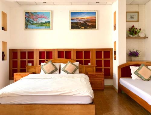大叻The One Home Đà Lạt的一间卧室配有两张床,墙上有两幅画作