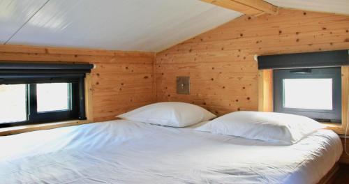 EstevaisTiny house eco resort的木制客房的一张床位,配有两个枕头