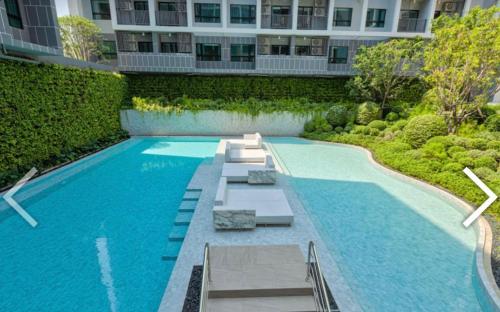 华欣DusitD2 Hua Hin 2- One bedroom with a beautiful view 8的大楼前带长椅的游泳池