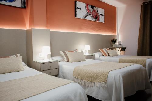 马拉加玛斯蒂尔16号旅馆的橙色墙壁的客房内的三张床