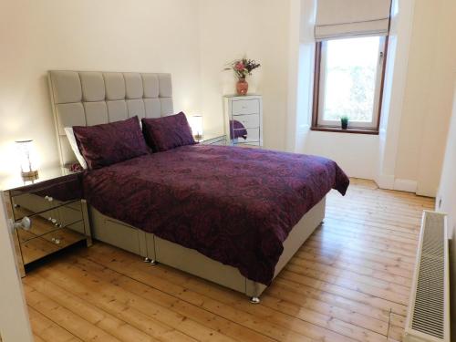 格拉斯哥Beautiful & spacious 2 bed apt in Glasgow West End的一间卧室配有一张带紫色床罩的床和窗户。
