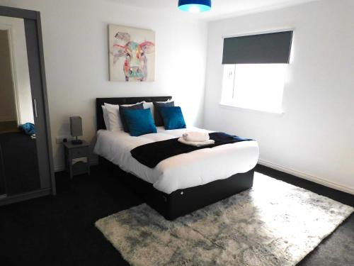 汉密尔顿Newly refurbished 2 bedroom apartment close to station and local amenities的一间卧室配有一张带蓝色枕头的床和一扇窗户。