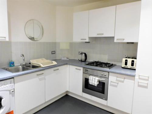 格拉斯哥2 Bedroom Apt in the Heart of the City Centre, perfect Location的厨房配有白色橱柜、水槽和炉灶。