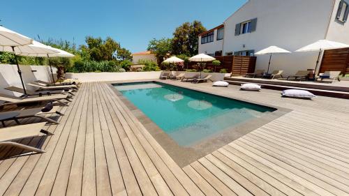 卡尔维Résidence Villa Branda的木制甲板上配有椅子和遮阳伞的游泳池