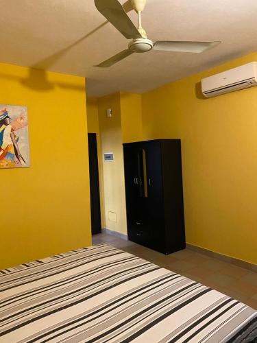 Abomey-CalaviAGENCE IMMOBILIÈRE GDS BENIN的客房拥有黄色的墙壁和吊扇。