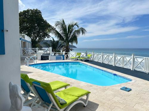 FrederikstedNorth Star Villa Oceanfront Family-Retreat With Pool的一个带椅子的游泳池,背景是大海