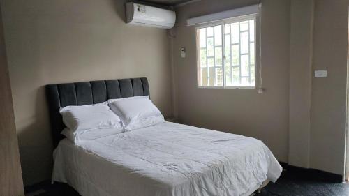 哥伦比亚港Casa de playa Puerto Colombia的一间卧室配有一张带白色床单的床和一扇窗户。