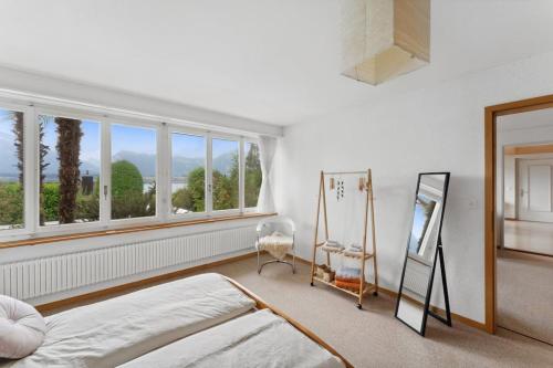 图恩湖畔上霍芬Lakeview apartment in beautiful Oberhofen的一间卧室设有一张床、一个窗口和一面镜子