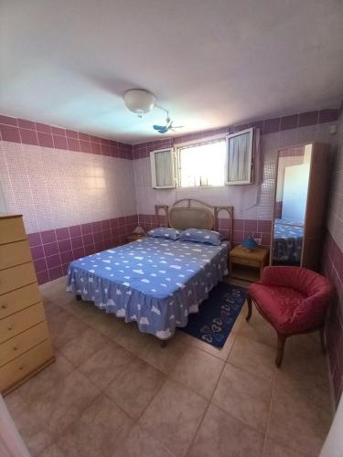 切萨雷奥港2 bedrooms property with shared pool at Porto Cesareo 1 km away from the beach的一间卧室配有一张床和一张红色椅子