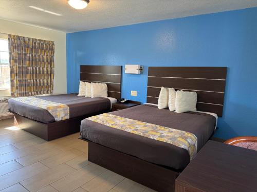 蓬塔戈尔达美国蓬塔戈尔达汽车旅馆的酒店客房设有两张床和蓝色的墙壁。
