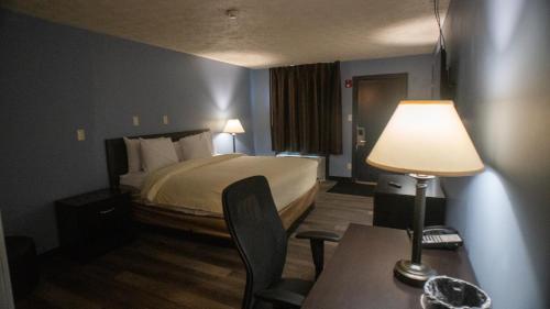 普兰菲尔德Ashley Motel的酒店客房配有一张床和一张带台灯的桌子