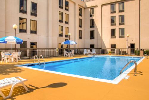 法兰克福法兰克福汉普顿酒店的一座带椅子和遮阳伞的游泳池位于一座建筑旁边