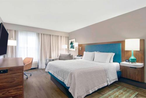 劳德代尔堡Hampton Inn Ft Lauderdale Airport North Cruise Port的酒店客房设有一张大床和一张书桌。