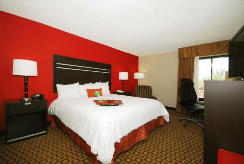 迈尔斯堡I-75迈尔斯堡机场汉普顿酒店的酒店客房设有一张大床和红色的墙壁。