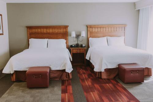 格林里弗绿河汉普顿酒店及套房的一间卧室配有两张带白色床单的床