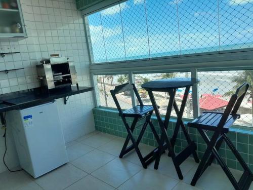 蒙加瓜Belíssimo apartamento frente mar的带窗户的厨房配有两把椅子和一张桌子