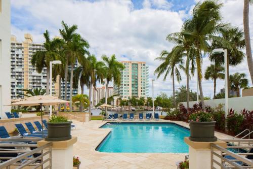 劳德代尔堡GALLERY One - A DoubleTree Suites by Hilton Hotel的一个带椅子和棕榈树的游泳池,以及建筑