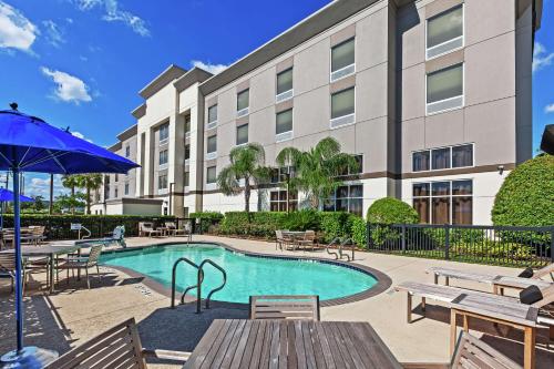 休斯顿乔治·布什洲际机场汉普顿套房酒店的一座带桌椅的游泳池以及一座建筑