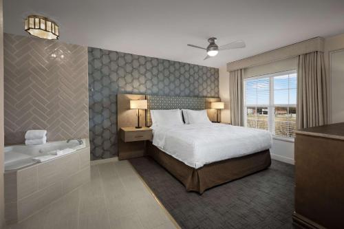 威奇托海滨希尔顿惠庭套房酒店的卧室设有一张床和一个靠窗的浴缸
