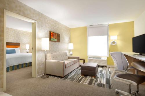 尤金尤金市中心大学区希尔顿欣庭套房酒店的酒店客房配有一张床、一把椅子和一张书桌