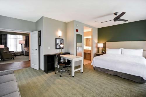 格林维尔Homewood Suites By Hilton Greenville Downtown的配有一张床和一张书桌的酒店客房