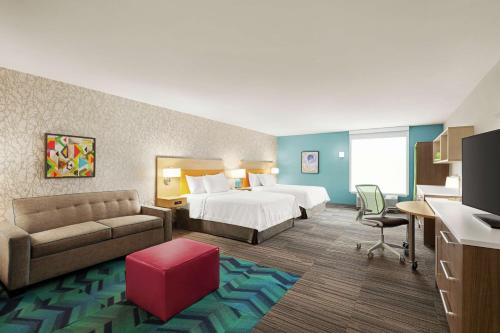 费南迪纳比奇Home2 Suites By Hilton Fernandina Beach on Amelia Island, FL的酒店客房,配有床和沙发