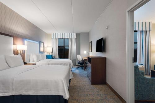 雷斯顿Homewood Suites By Hilton Reston, VA的酒店客房设有两张床和电视。
