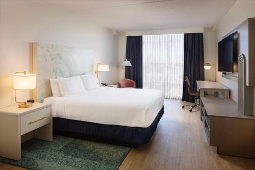 达尼亚滩Hotel Dello Ft Lauderdale Airport, Tapestry Collection by Hilton的酒店客房设有一张大床和一张书桌。