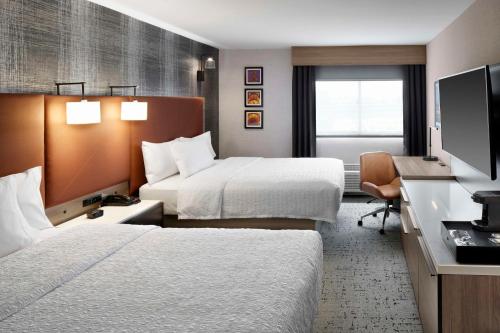 纽瓦克Hampton Inn Newark Airport的酒店客房配有两张床和一张书桌
