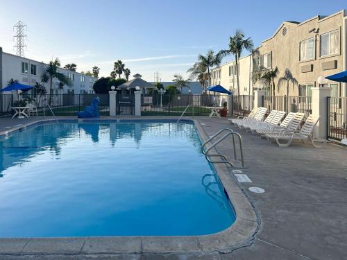 卡森Studio 6 Carson, CA的一座带椅子和建筑的大型蓝色游泳池