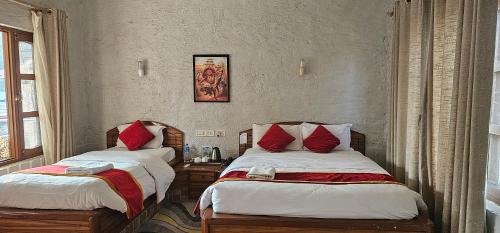 索拉哈Jungle Safari Lodge - Chitwan National Park,Sauraha的一间卧室配有两张带红色枕头的床