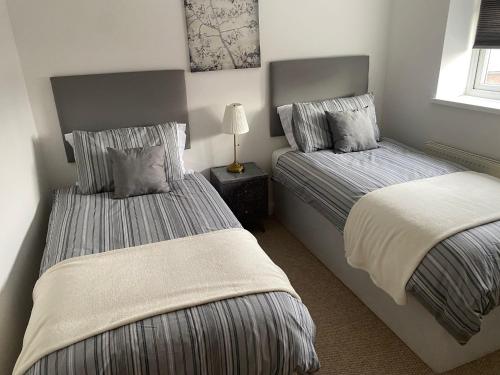 伯明翰Aston Apartment 4 -Secure Parking的一间卧室设有两张床和一张桌子上的台灯。