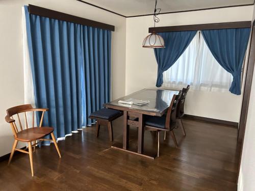 富士吉田市Guest House Fuji no Yado Akebono Building A - Vacation STAY 74316v的一间设有蓝色窗帘和桌椅的用餐室