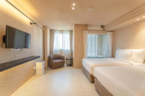 清迈Mai Hotel的酒店客房设有两张床和一台平面电视。