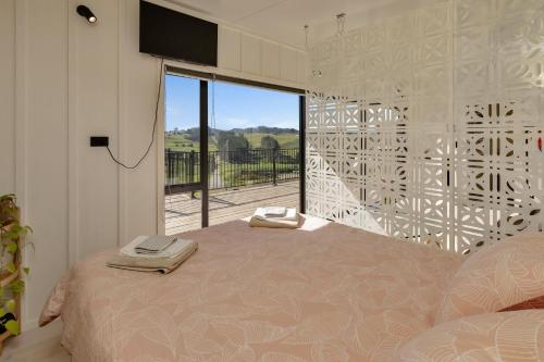 旺阿雷Valley View - Whangarei Tiny Home的一间卧室设有一张床和一个大窗户