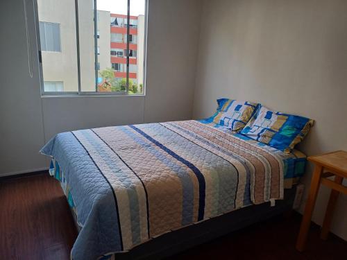 利马Habitación acogedora Orué的一间卧室配有一张带蓝色枕头的床和一扇窗户。